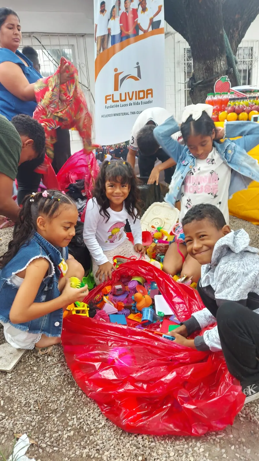 Niños y niñas revisan los juguetes donados junto al banner de Fluvida