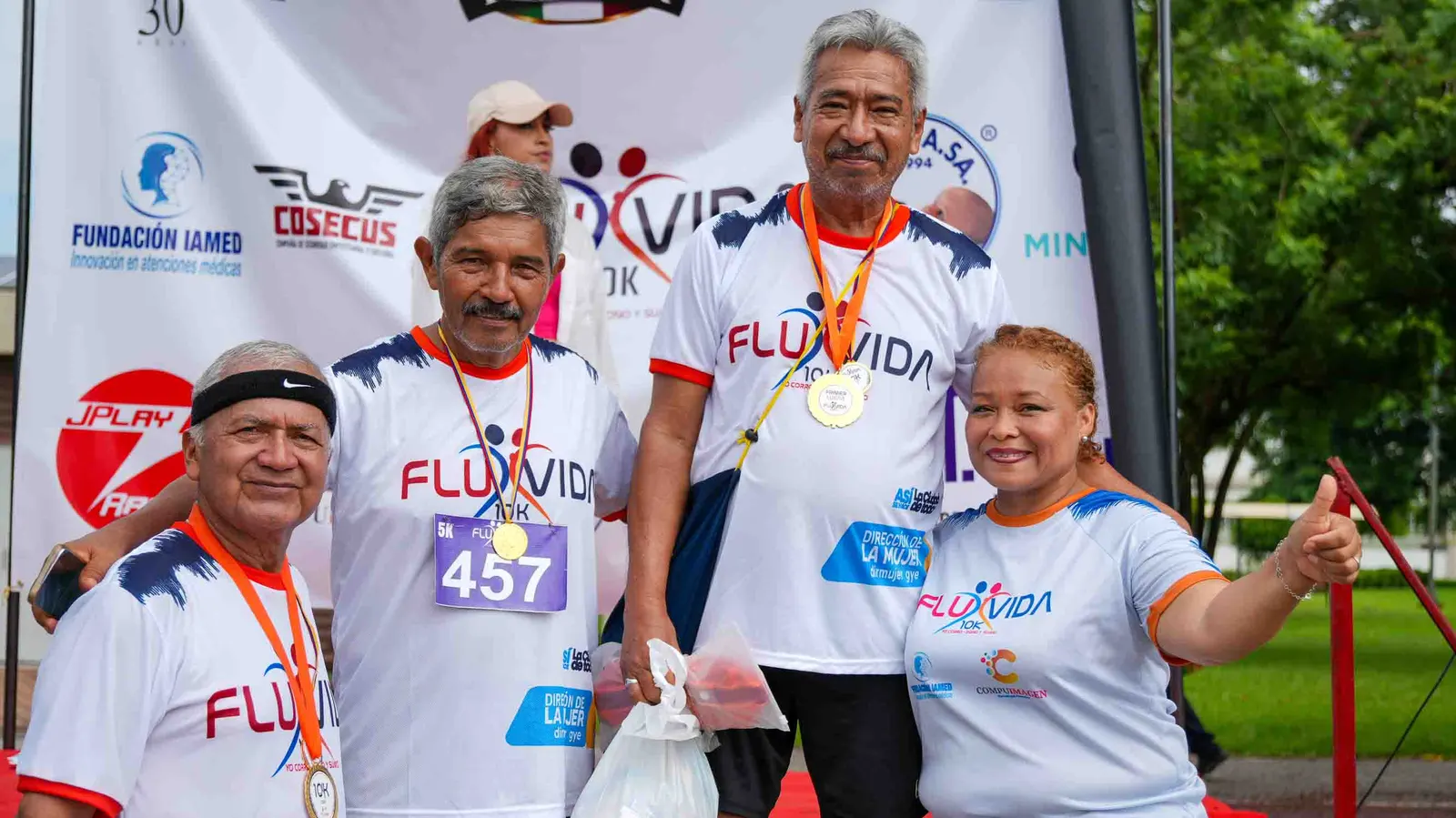 Corredores con sus medallas de la Carrera Fluvida 10K junto a una organizadora