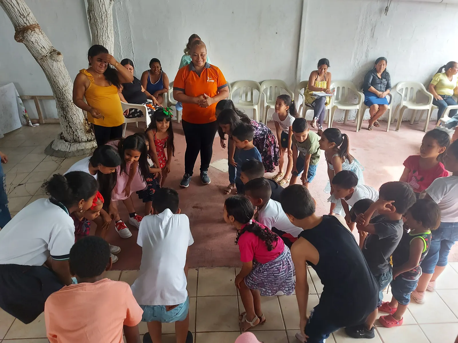 Niños y niñas en círculo durante una dinámica del taller, guiados por una voluntaria de Fluvida