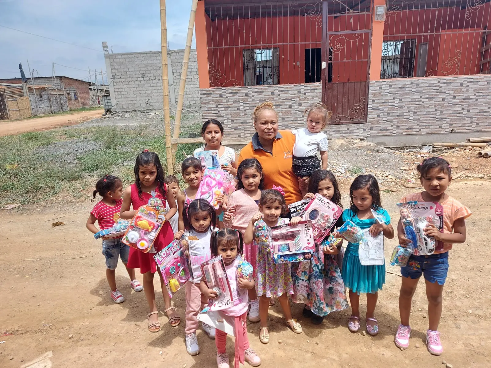 Niñas de la comunidad sonríen con los regalos que recibieron, junto a una voluntaria de Fluvida